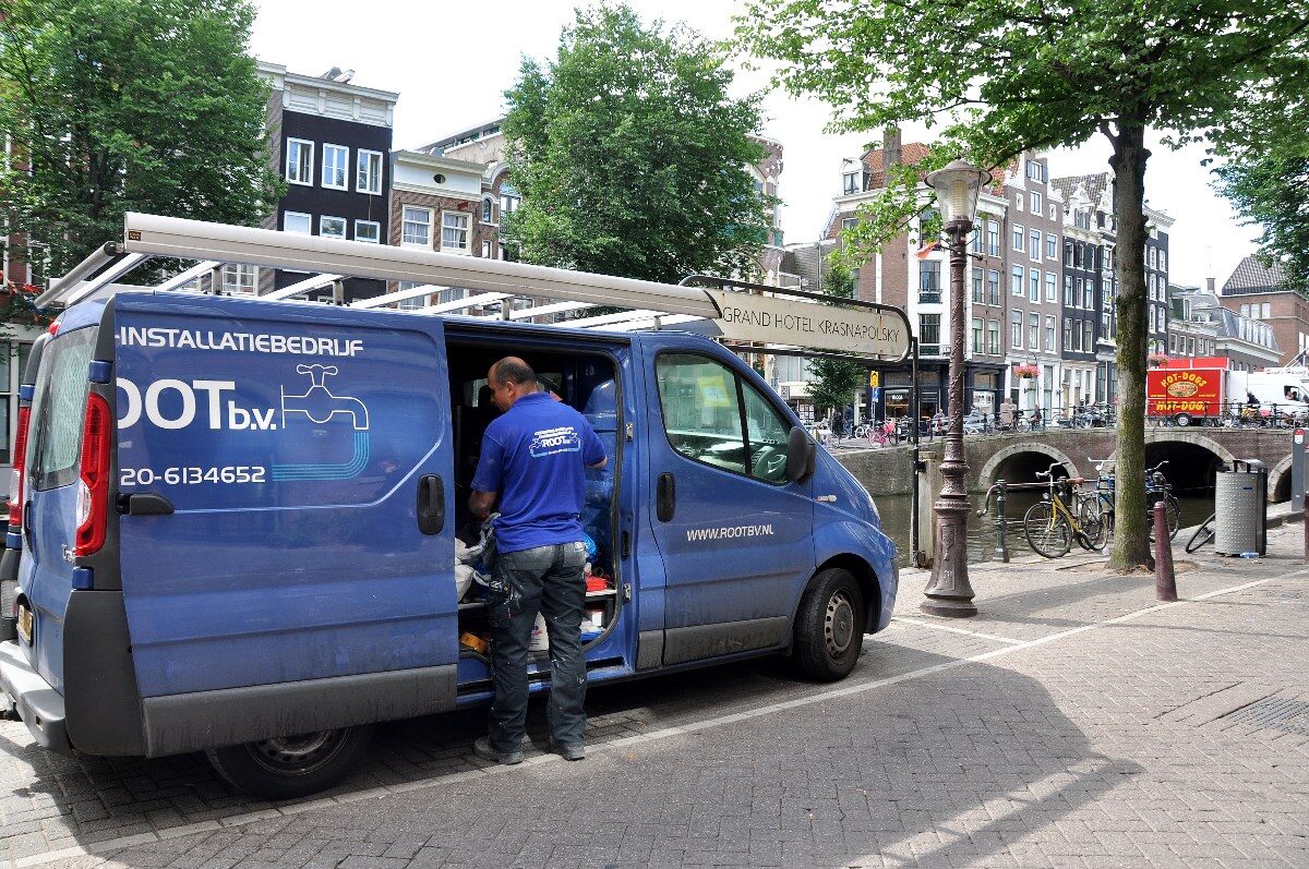 Monteur van Root bij de bedrijfsbus aan de gracht